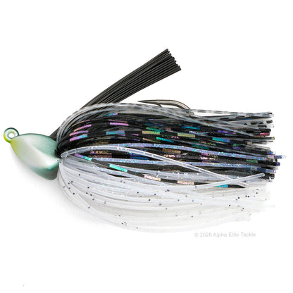 A fishing jig lure with a metallic green and gold blade, black split hooks, and dual-colored skirts. The skirt features a top band of black strands and a bottom band of translucent white strands with fine black glitter.