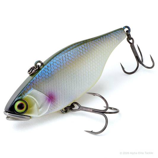A hard bait fishing lure with a realistic fish design, featuring a silver and blue-green back, a cream belly, a purple accent near the gill, and a detailed eye. It is equipped with two treble hooks and photographed on a clean white background.