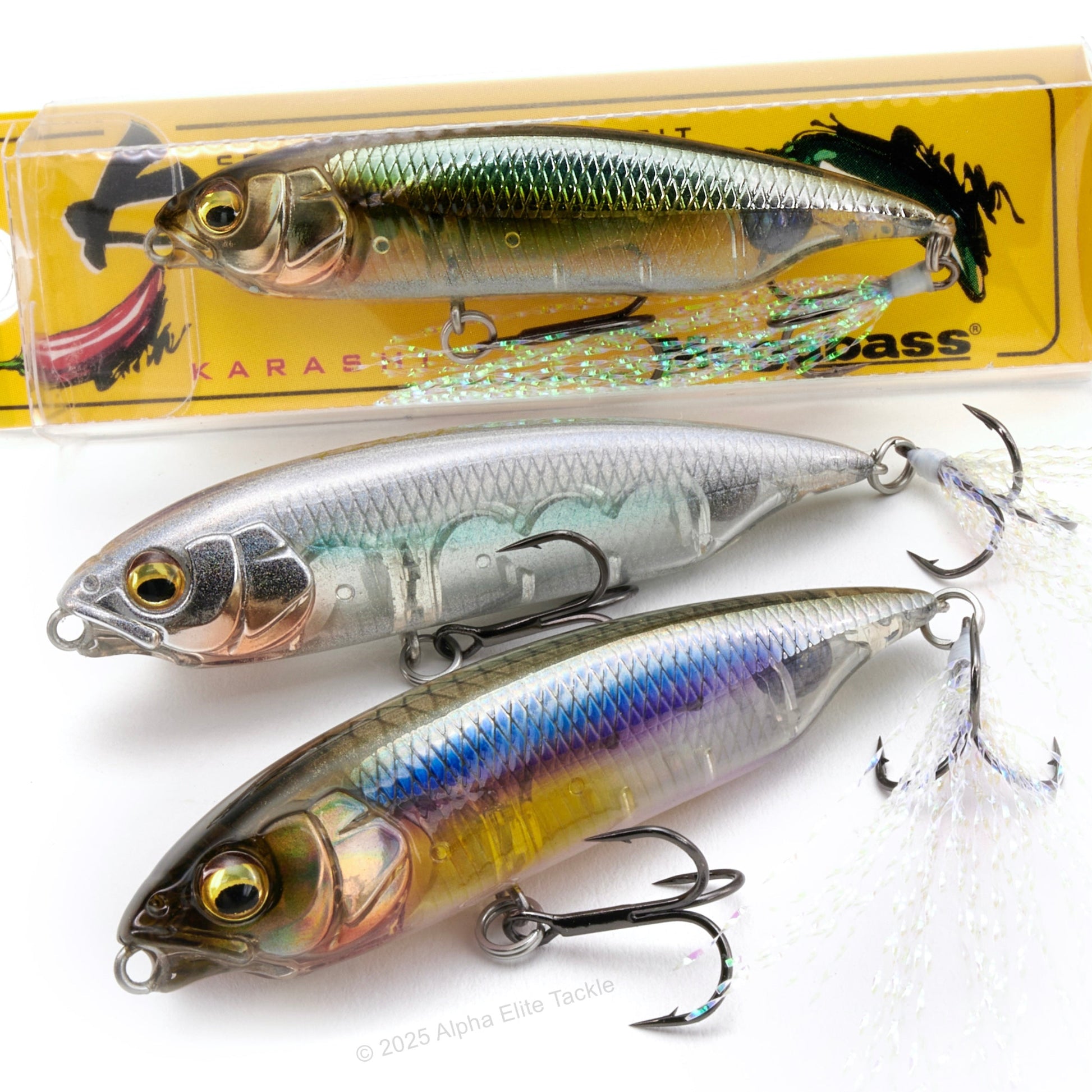 Three colorful fishing lures on a white surface with a branded box in the background.