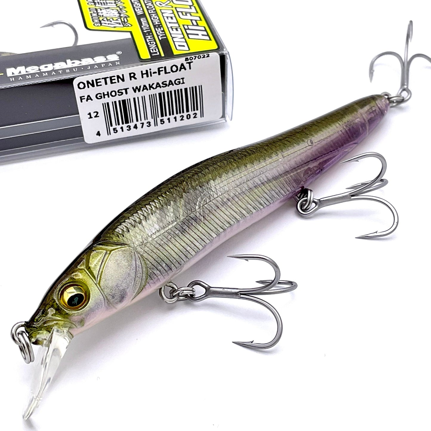 Fishing lure with treble hooks next to its packaging on a white background