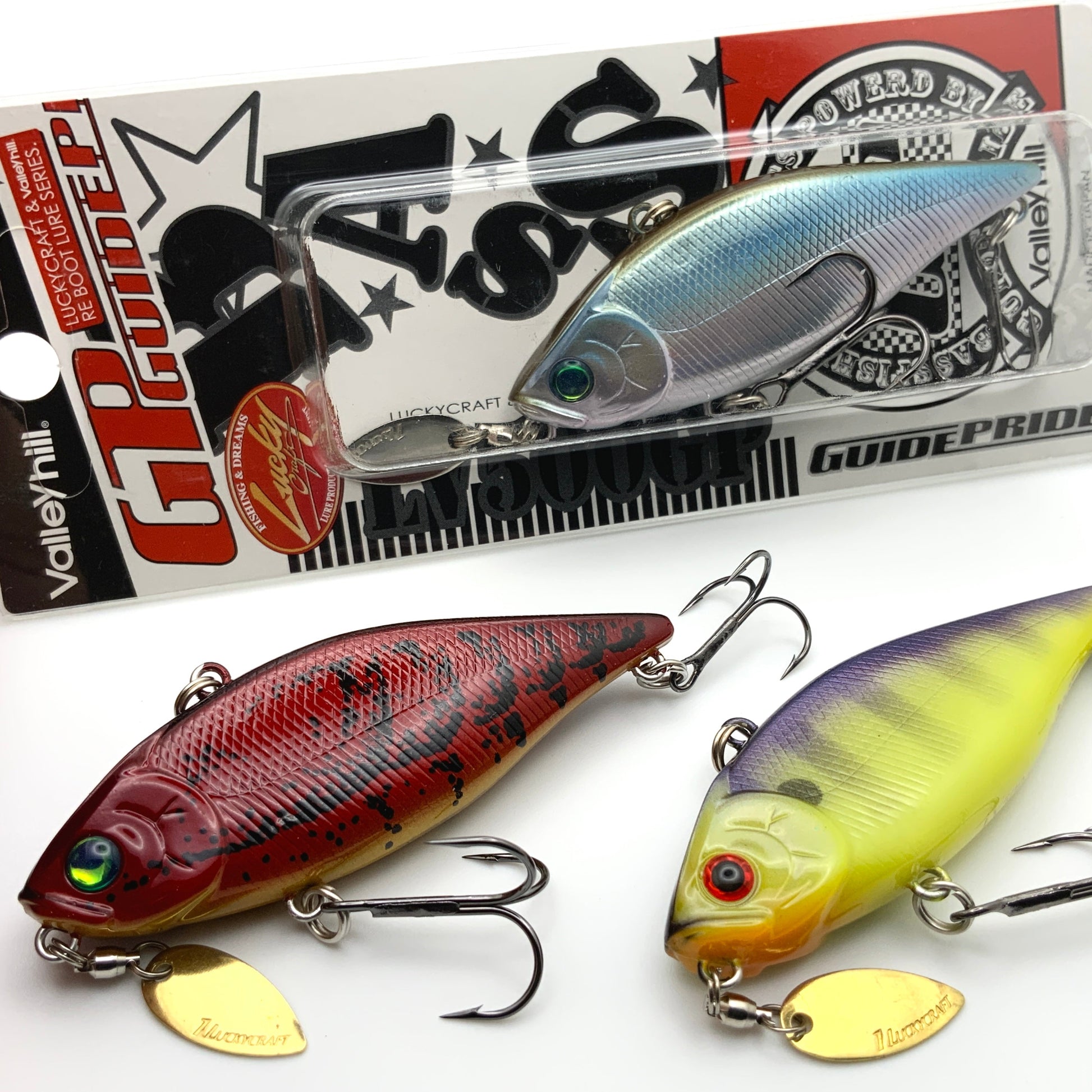 Three fishing lures on a white background with packaging in the background.